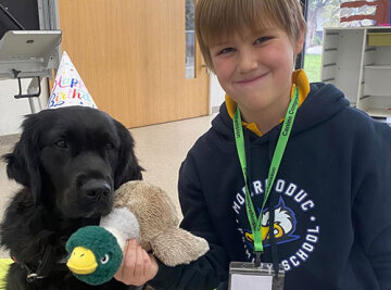 Child in a school uniform with a therapy dog.